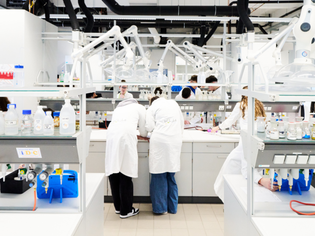 Großaufnahme eines Labors mit Rückensicht von zwei Personen in Labormänteln in der Mitte
